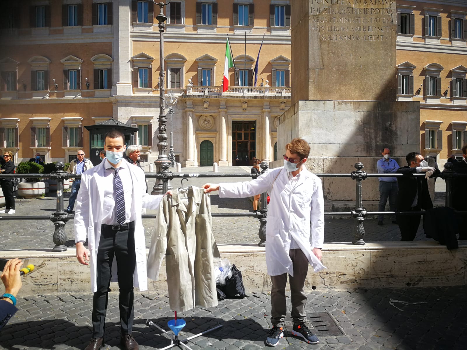 Spalle al palazzo e via il camice, la protesta degli specializzandi a Montecitorio: «Troppe poche borse, si rischia un esercito di camici grigi»
